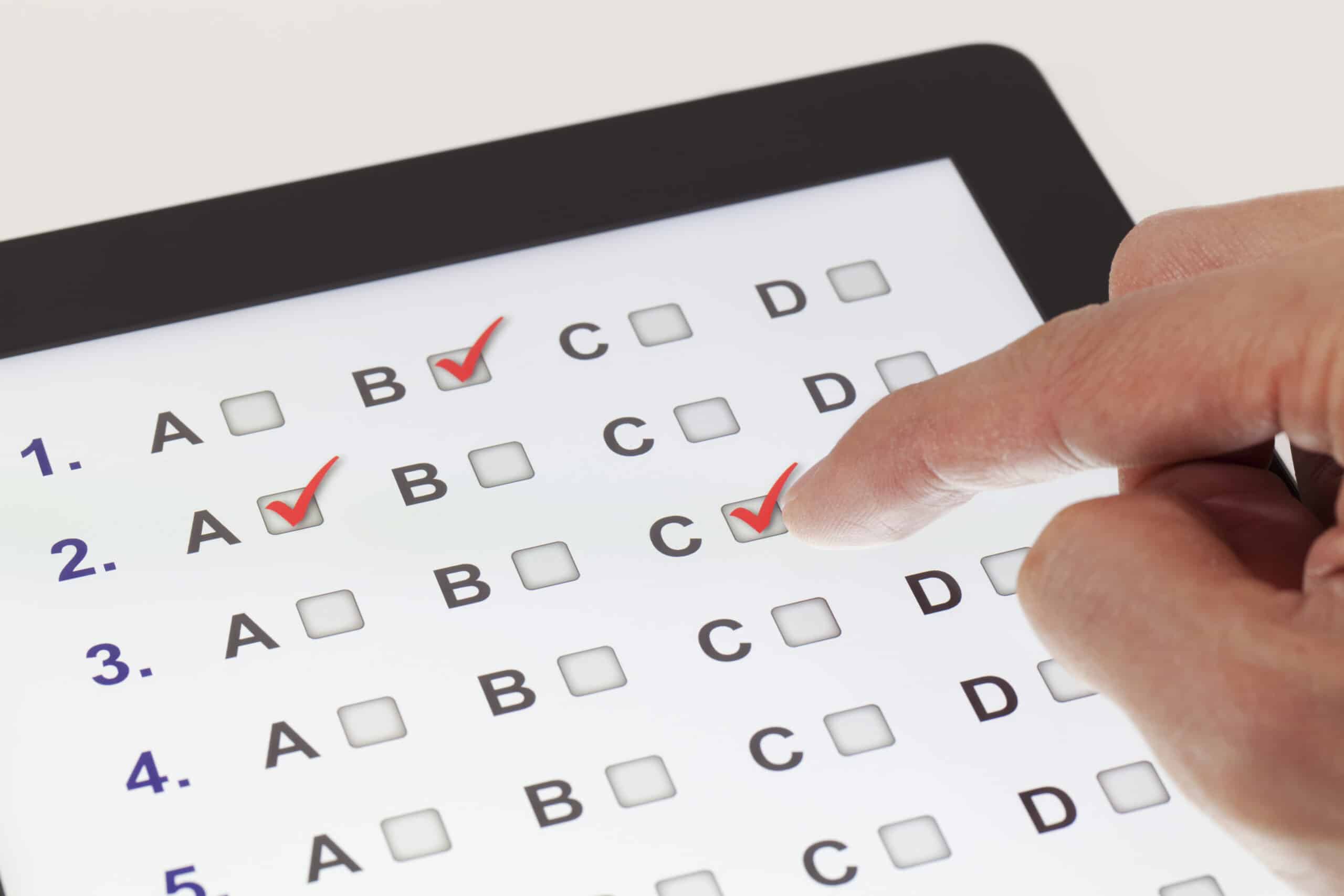 Finger wählt auf einem Tablet verschiedene Antworten von Multiple-Choice-Fragen aus.